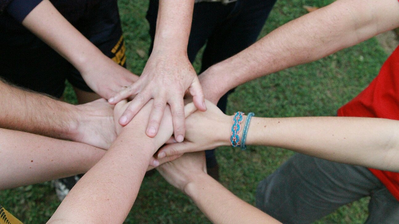 handen van acht mensen op elkaar gestapeld